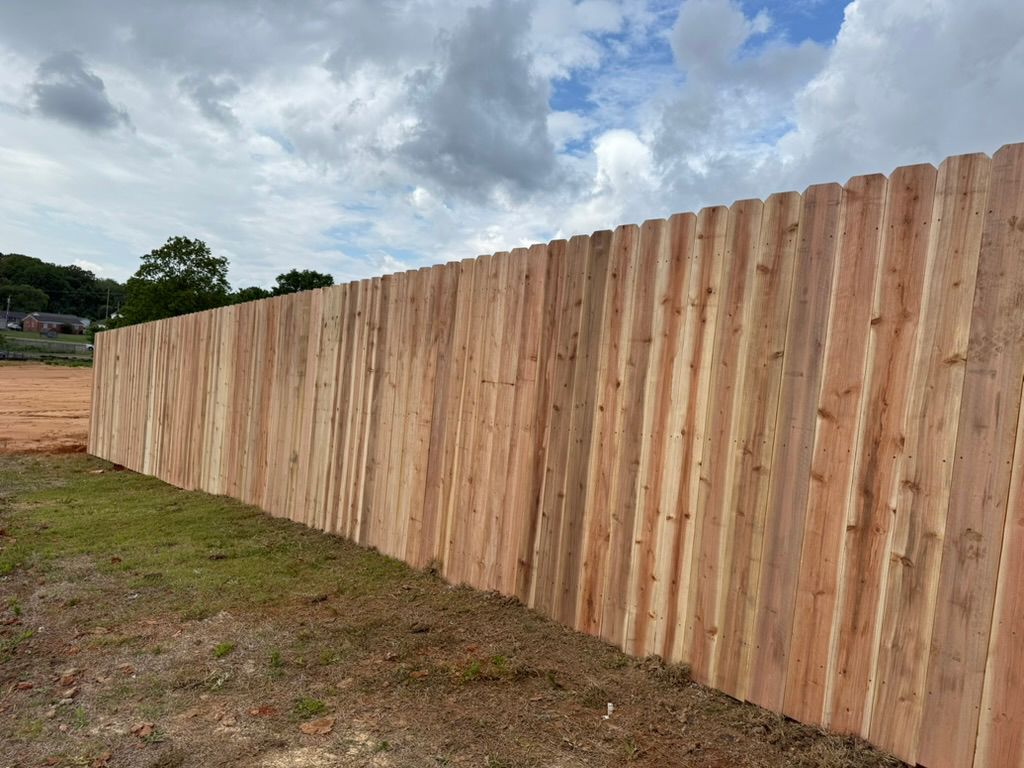 Wooden fence against cloudy sky and grass.