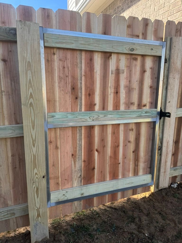 Wooden fence with a gate, metal frame, and black latch.