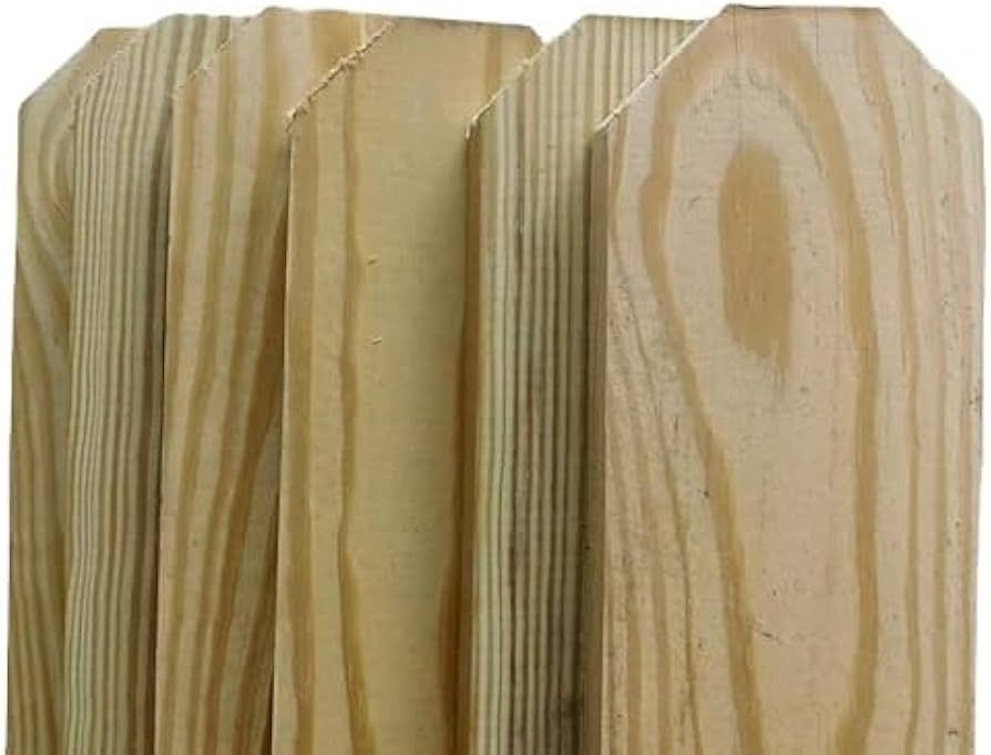 Close-up of several light-colored wooden fence pickets with rounded tops, showing wood grain.