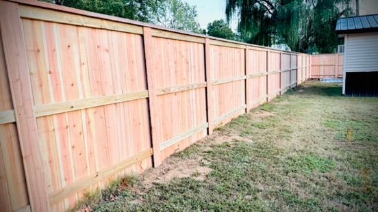 Wooden privacy fence in a grassy backyard.