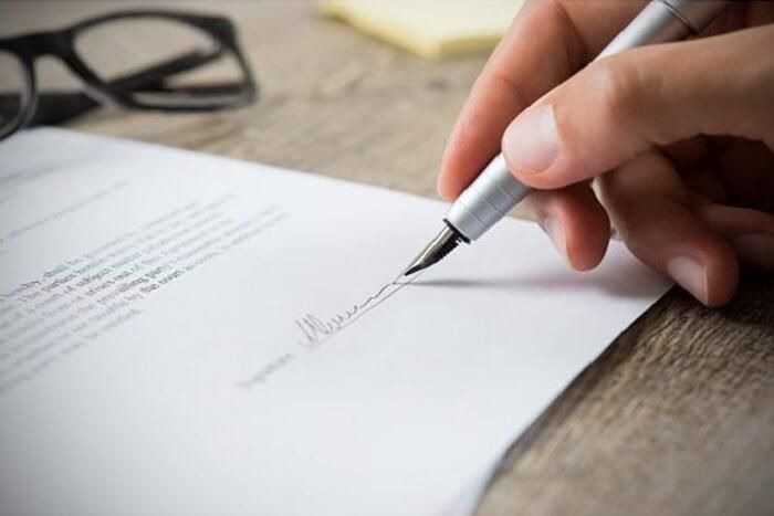 Una persona está firmando un documento con una pluma estilográfica.