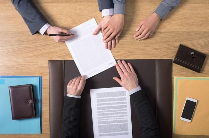 Un grupo de personas está sentada en una mesa firmando un documento.