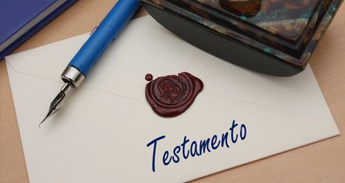 Una pluma estilográfica se encuentra encima de un sobre con la palabra testamento escrita en él.