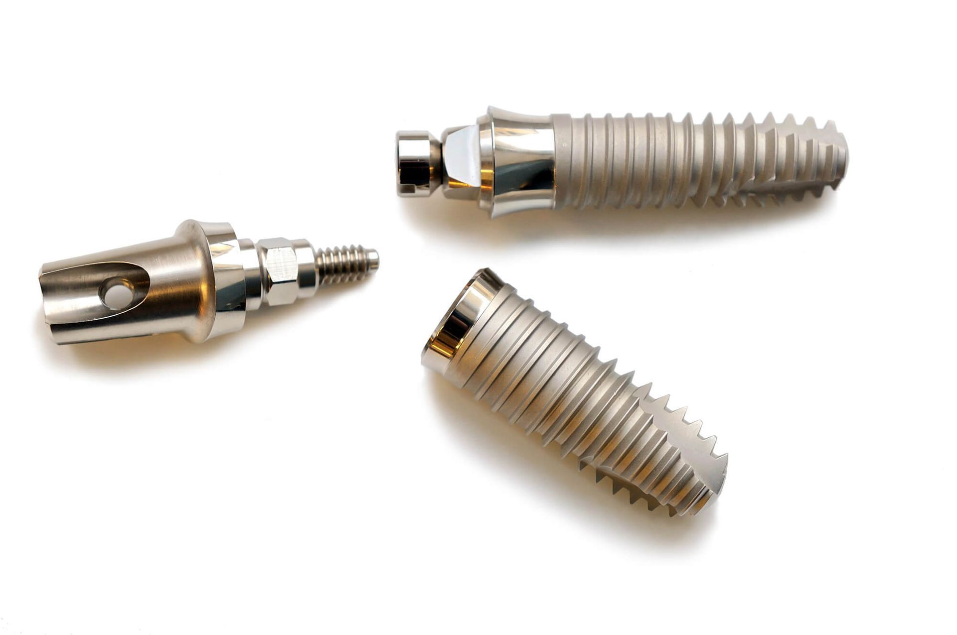 Three dental implant components on white background.