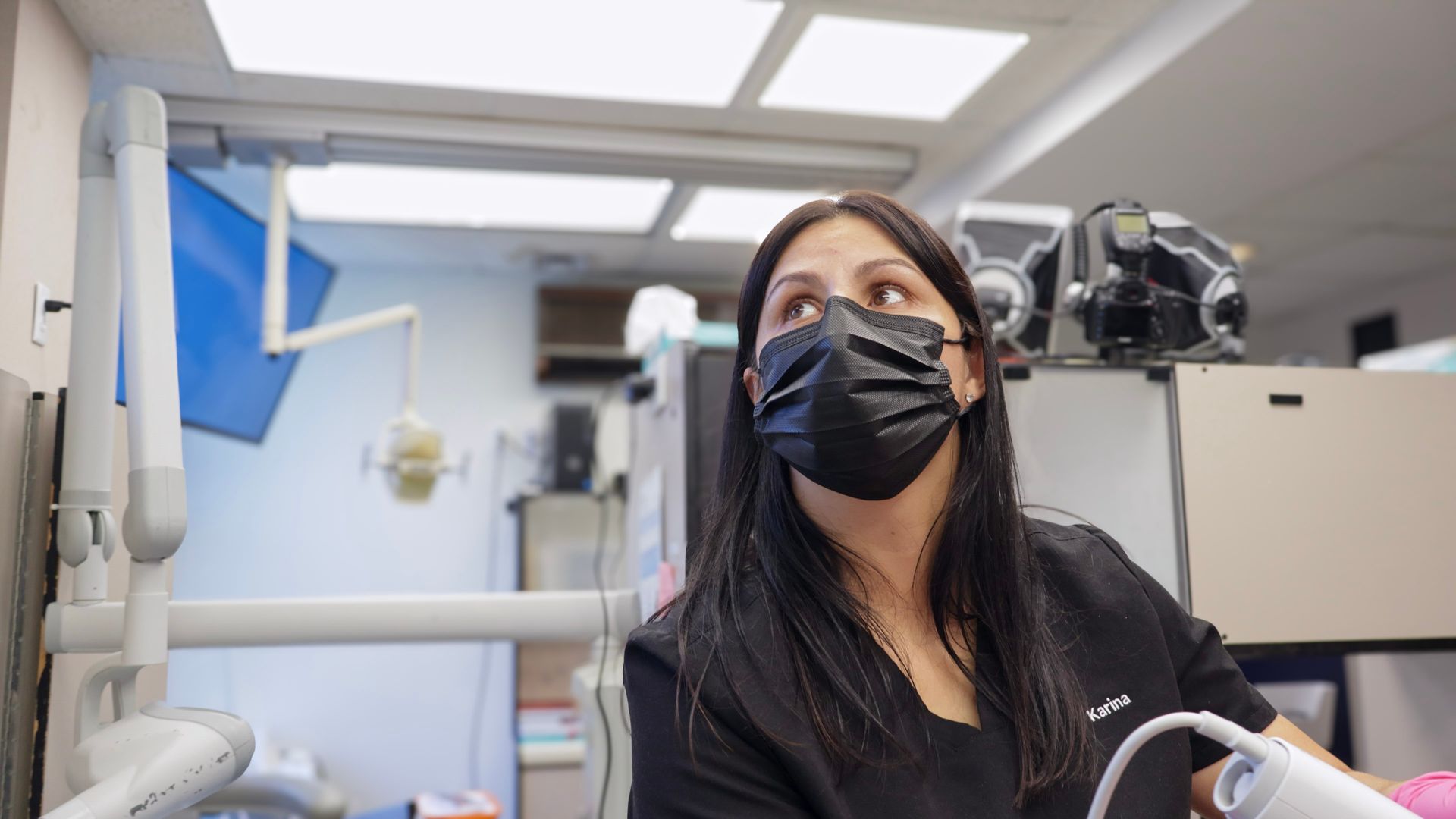 Dentist in black mask looking up in a dental office.