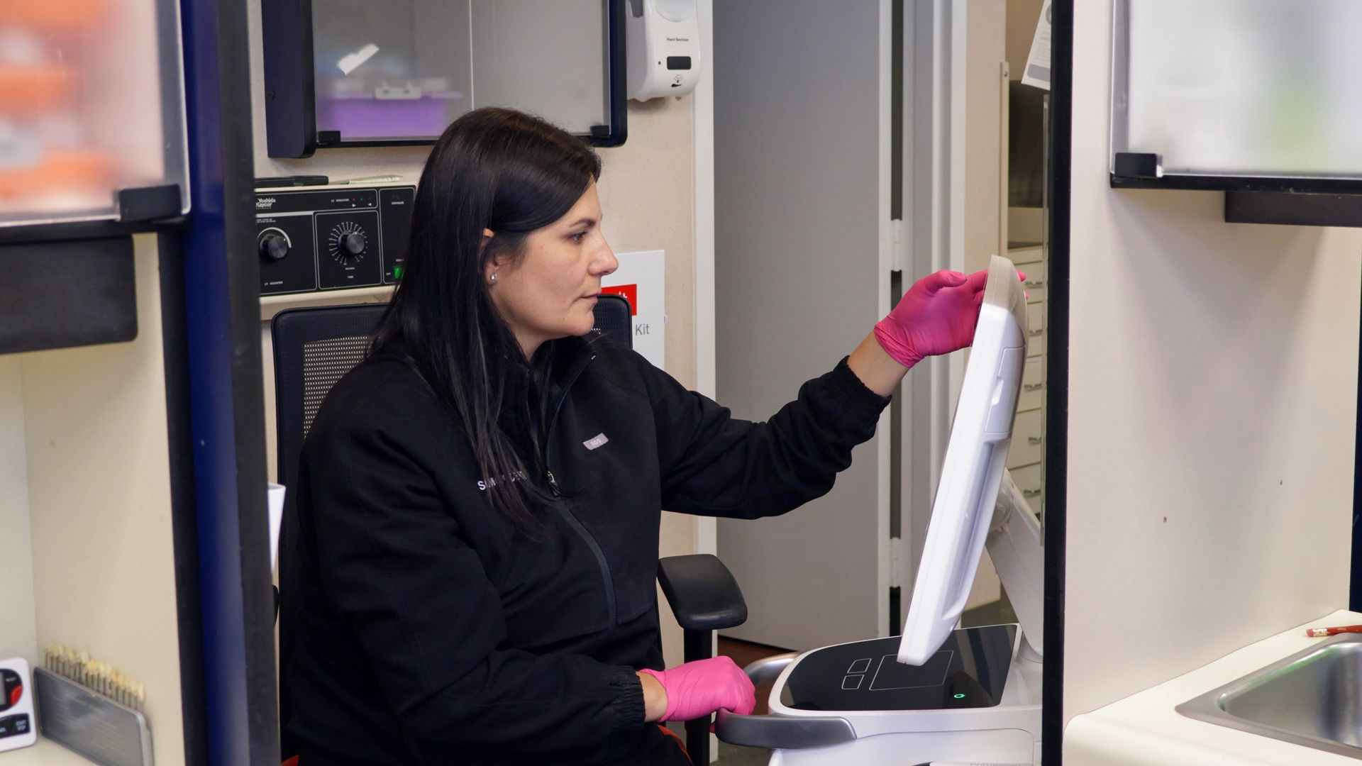 Woman in pink gloves at a computer in a dental office.