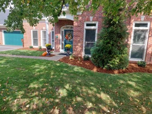 A Brick House with a Lush Green Lawn and a Blue Garage Door – Louisville, KY – Wayne's Lawn Service