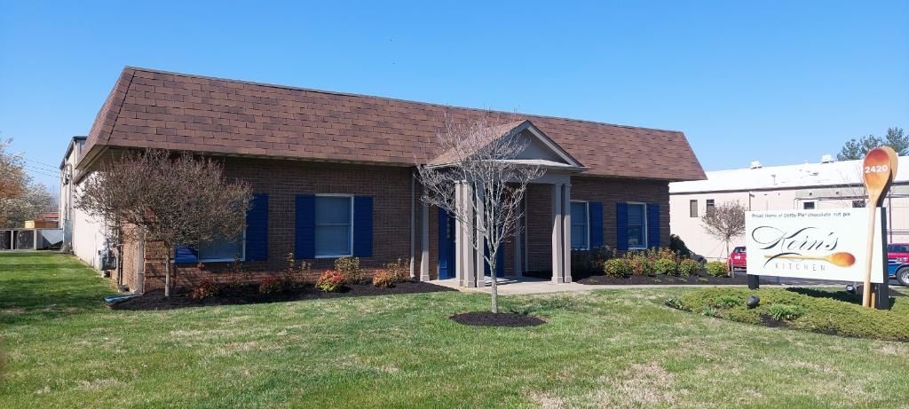 A House with a Brown Roof and Blue Shutters is Sitting on Top of a Lush Green Field – Louisville, KY – Wayne's Lawn Service