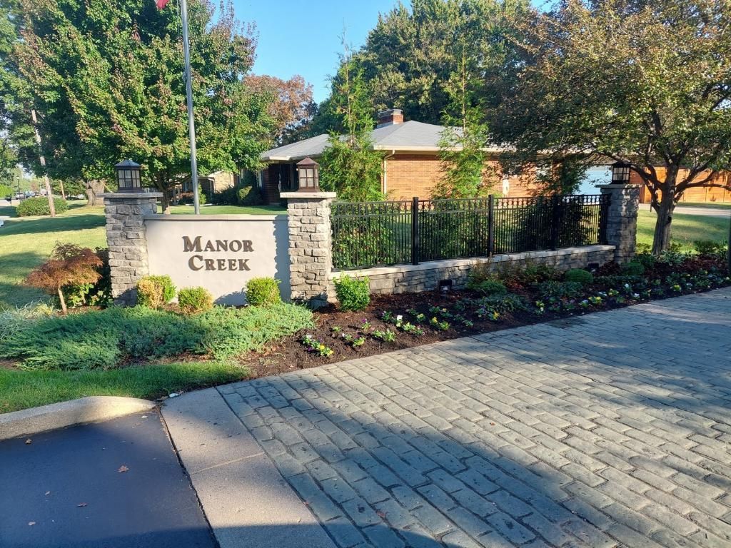 A Brick Driveway with a Sign that says Manor Creek – Louisville, KY – Wayne's Lawn Service