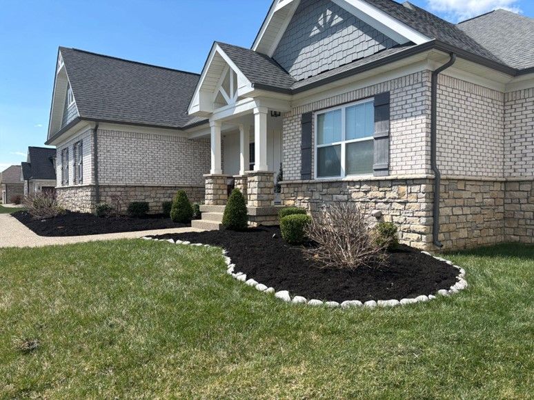 A white brick house with a gray roof and black shutters is sitting on top of a lush green lawn.