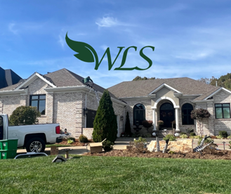 A white truck is parked in front of a house with a wls logo