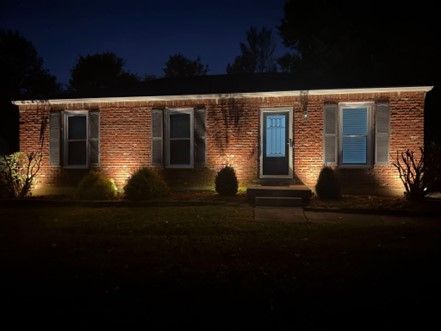 The front of a brick house is lit up at night.