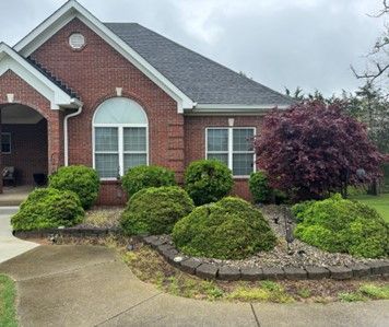A brick house with a lot of bushes in front of it