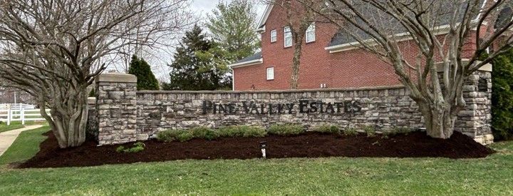 A brick wall with a sign in front of a brick house.