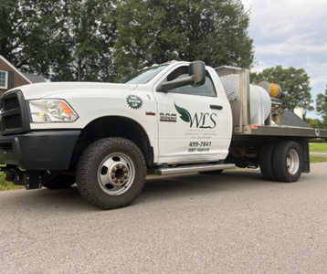 A white truck with wcs written on the side is parked on the side of the road