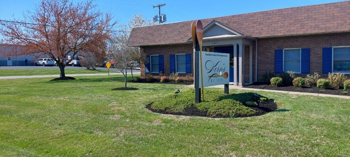 A brick building with blue shutters and a sign in front of it.