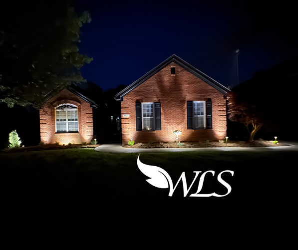 A brick house is lit up at night with a wls logo