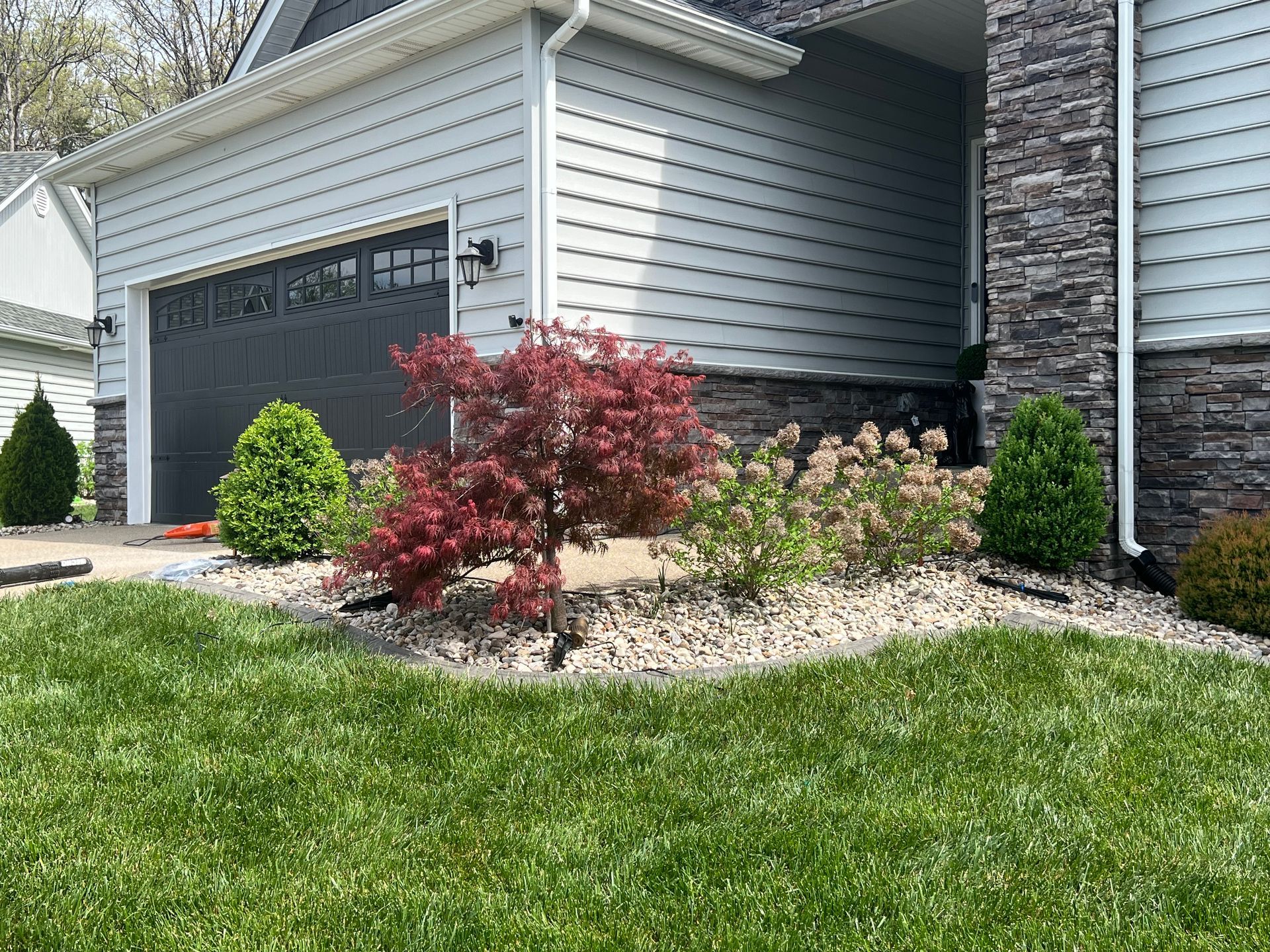 A House with a Garage and a Lush Green Lawn in front of it – Louisville, KY – Wayne's Lawn Service