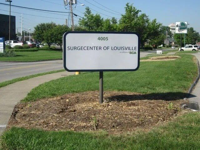 Sign for Surcenter of Louisville with address 4805. The sign is white with a black border, set in a landscaped area.