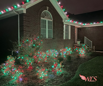House with Christmas lights on the roof and bushes. Red and green lights glow on bushes. House with Christmas lights on the roof and bushes. Red and green lights glow on bushes.