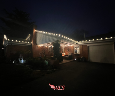 A house at night illuminated by white lights outlining the roof and porch, with a dark driveway. A house at night illuminated by white lights outlining the roof and porch, with a dark driveway.