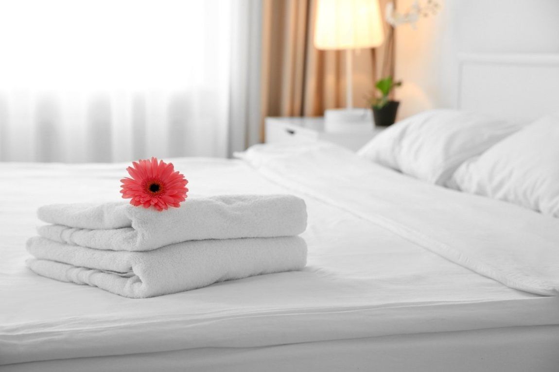 asciugamano bianco sul letto con un iore rosso