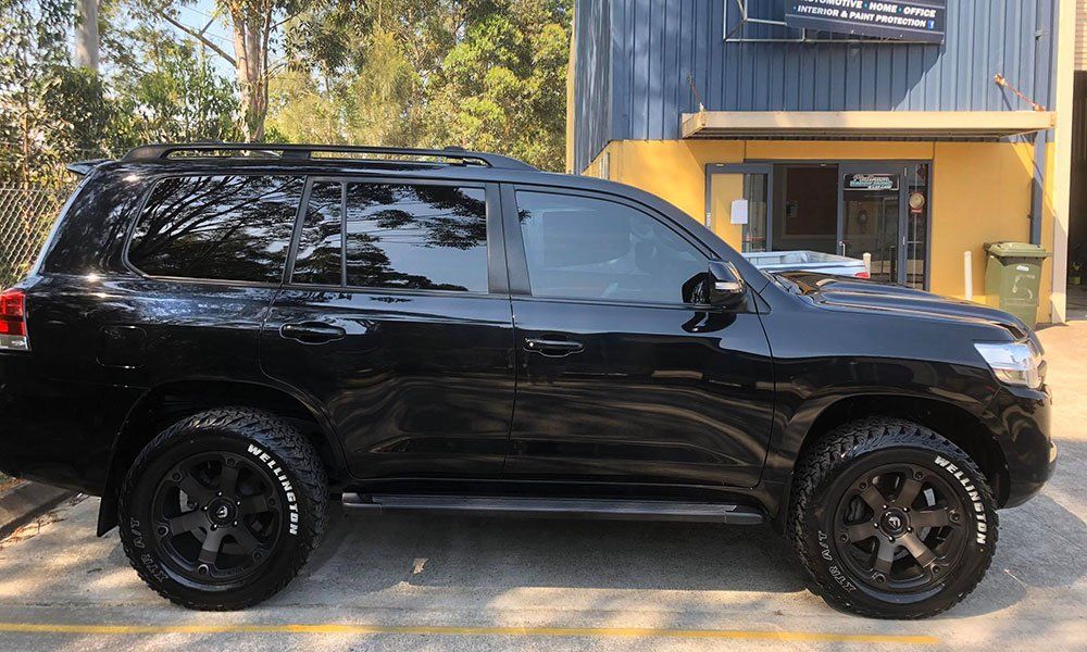 A black suv is parked in front of a building.