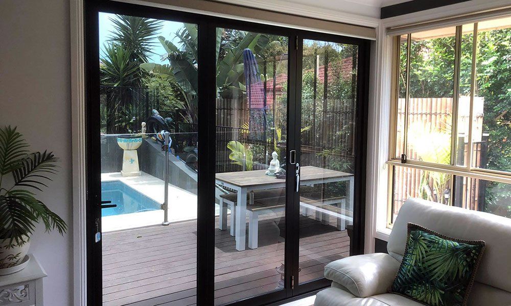 A living room with a couch and sliding glass doors leading to a pool.