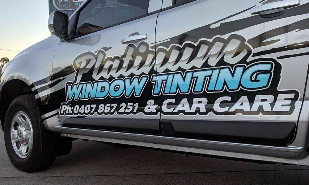 A silver truck with platinum window tinting and car care written on it