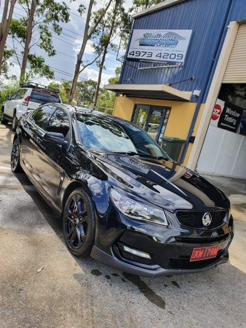 A black car is parked in front of a building with the number 4373 4209 on it