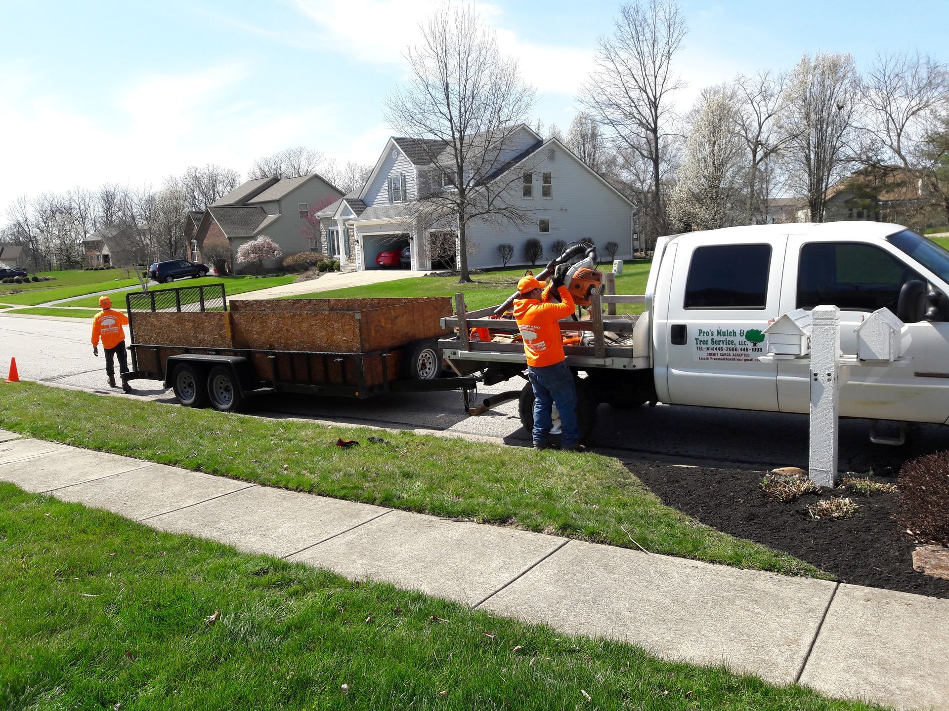 A white truck with a trailer attached to it is parked on the side of the road.