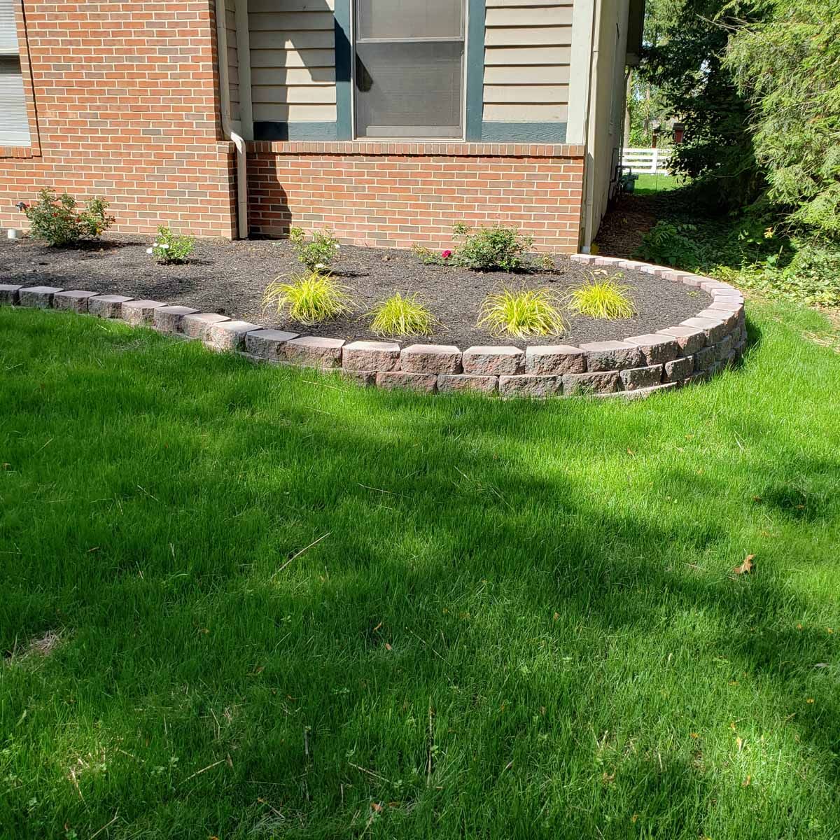 A brick house with a lush green lawn in front of it.
