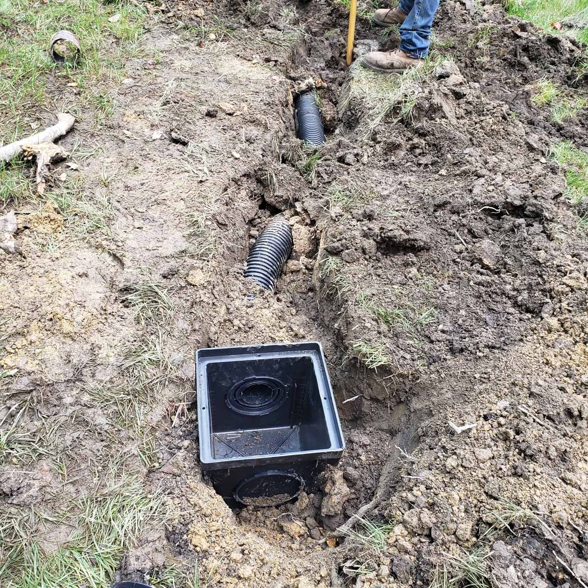 A man is digging a hole in the ground to install a septic system.