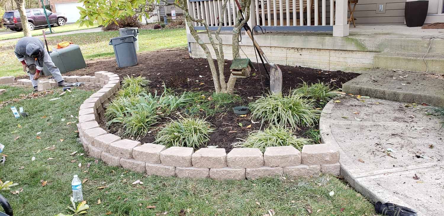 A man is working on a garden in front of a house.