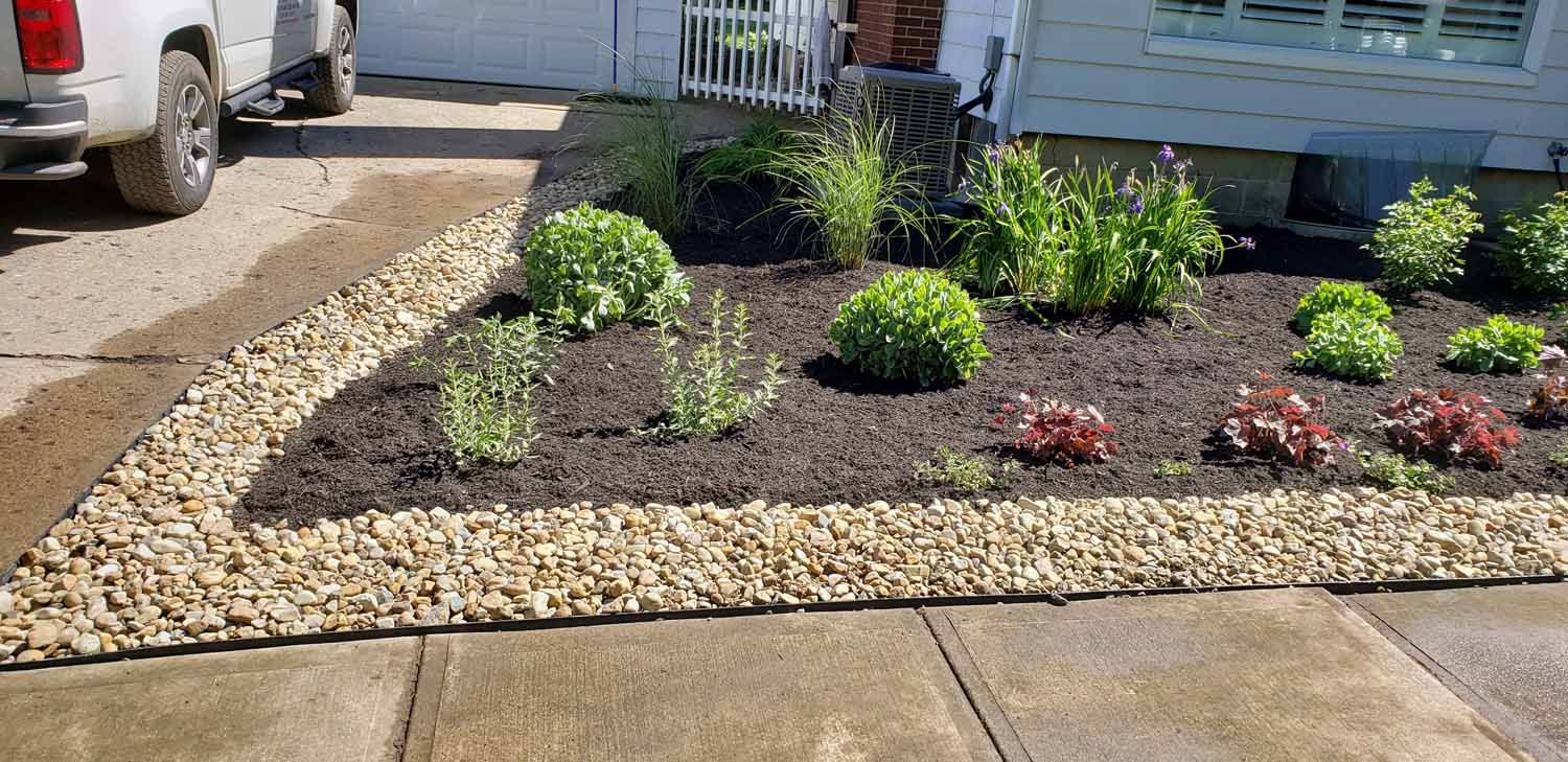 A white truck is parked in a driveway next to a garden.