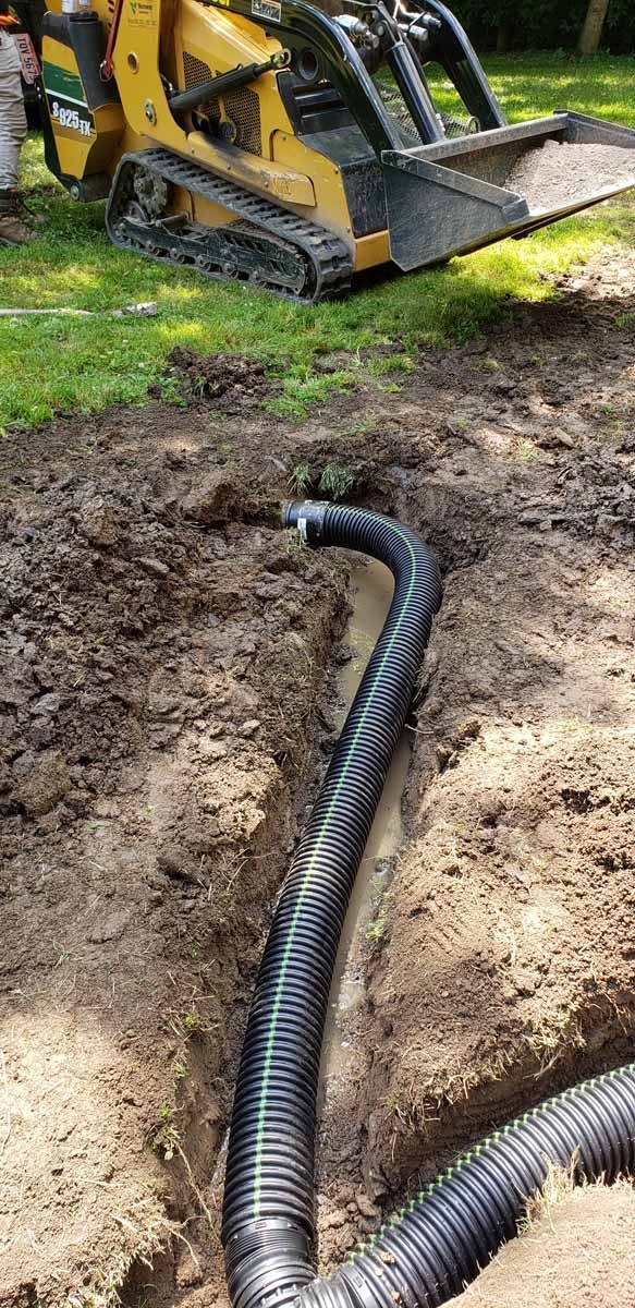 A bulldozer is digging a hole in the ground with a hose attached to it.