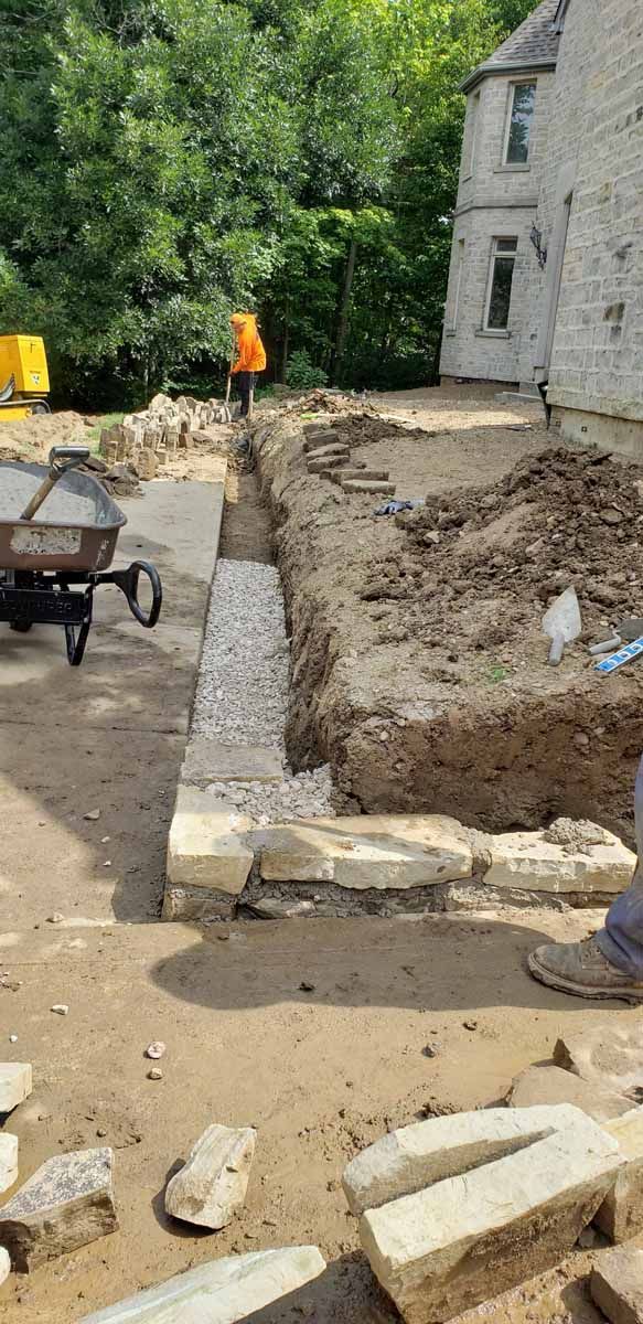 A construction site with a wheelbarrow and bricks in front of a house.