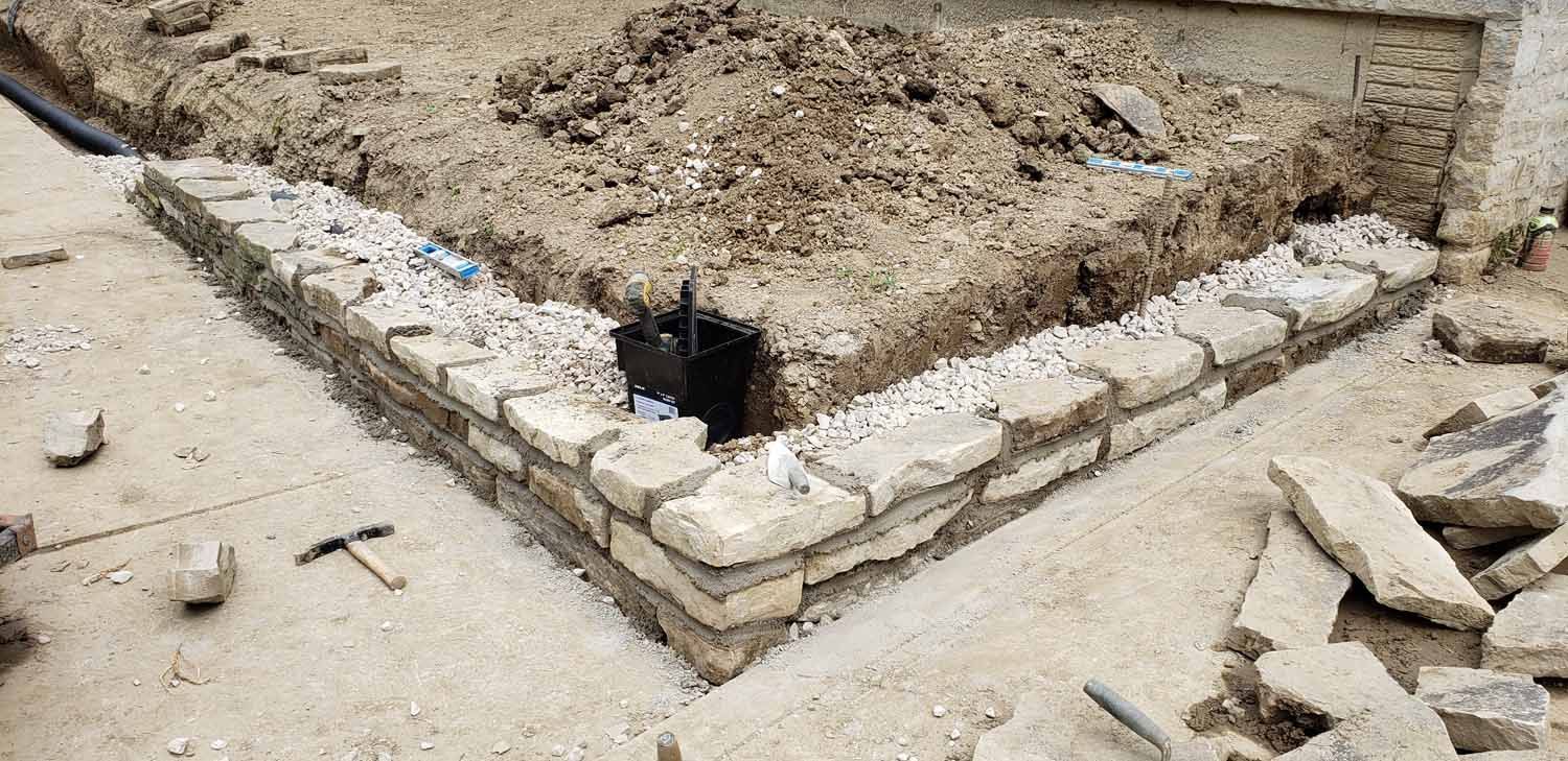 A brick wall is being built on the side of a road.