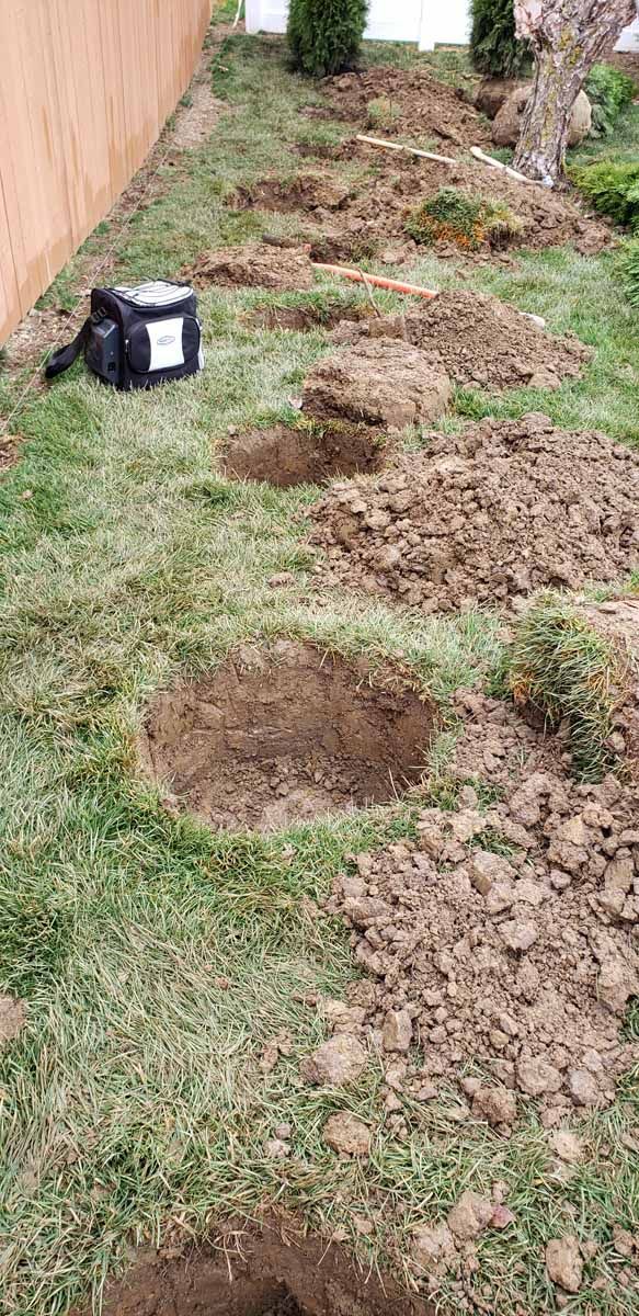 A bag is sitting on the ground next to a bunch of holes in the grass.