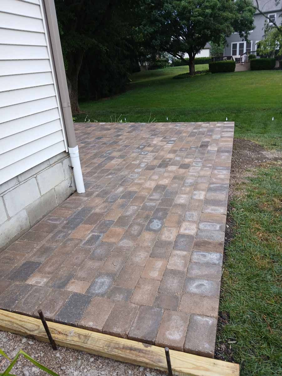 A patio is being built in the backyard of a house.