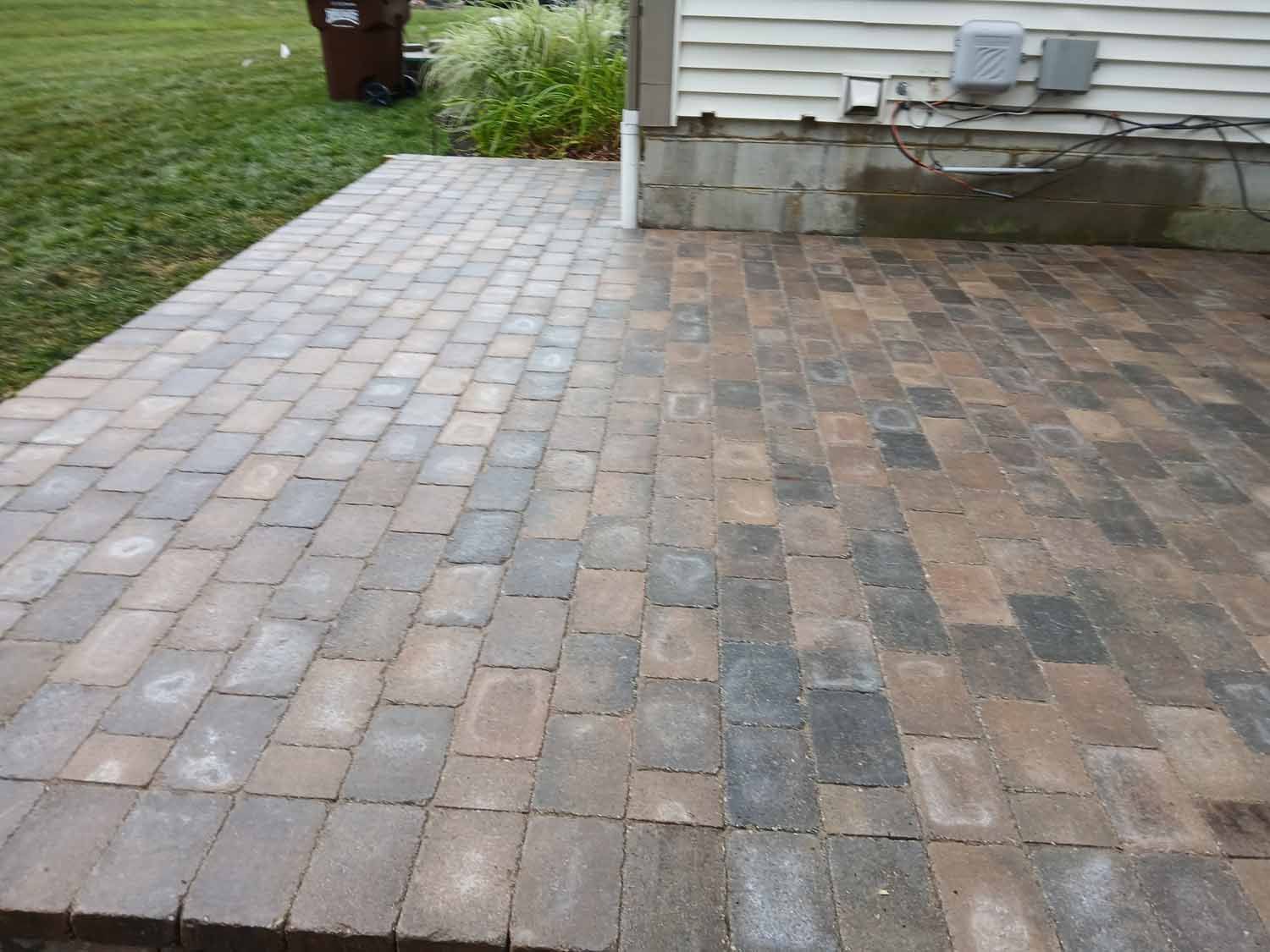 A brick patio with a white house in the background