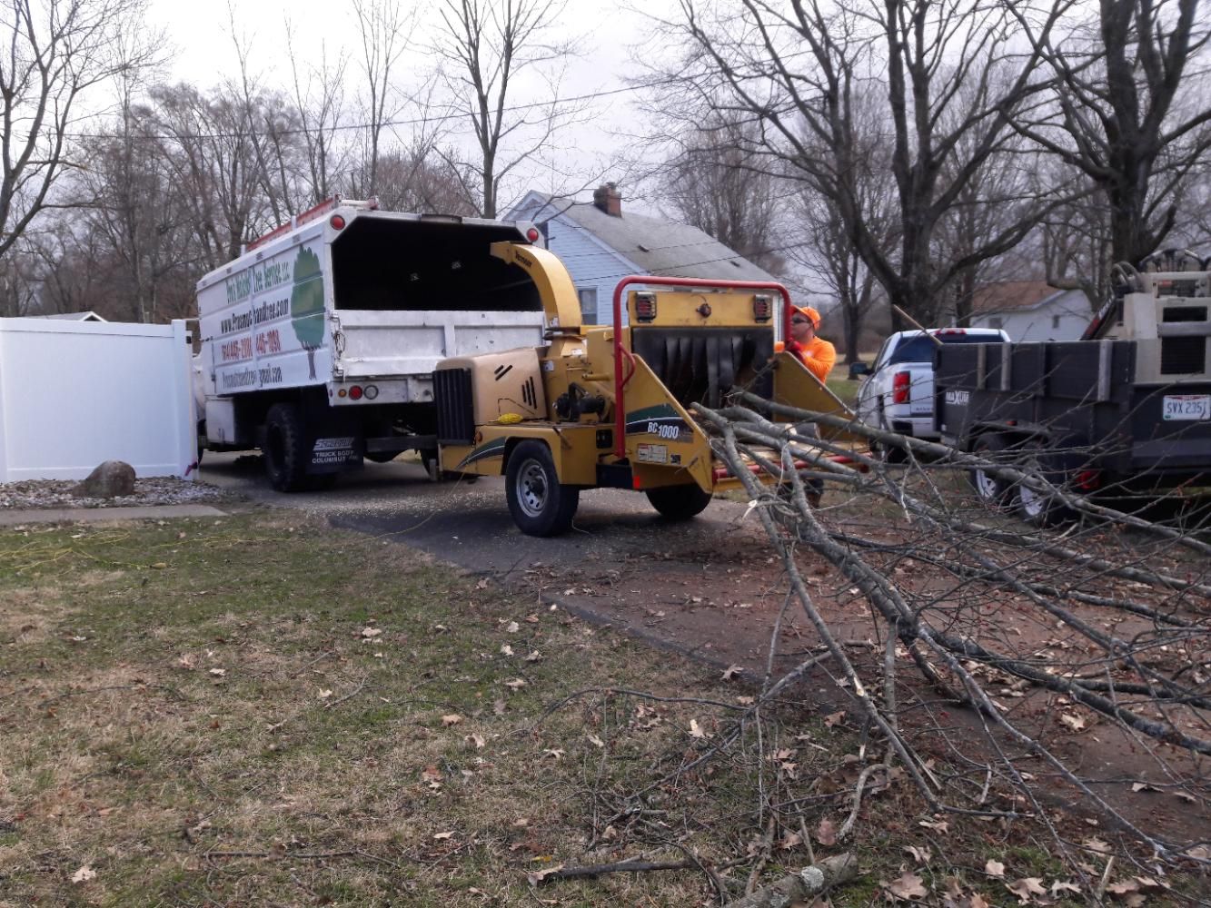 A tree chipper is attached to a truck in a yard