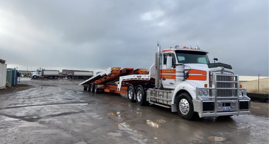 A Large Yellow Excavator Is Being Transported On A Flatbed Trailer – Warrnambool, VIC - McKinnon Quarries & Civil