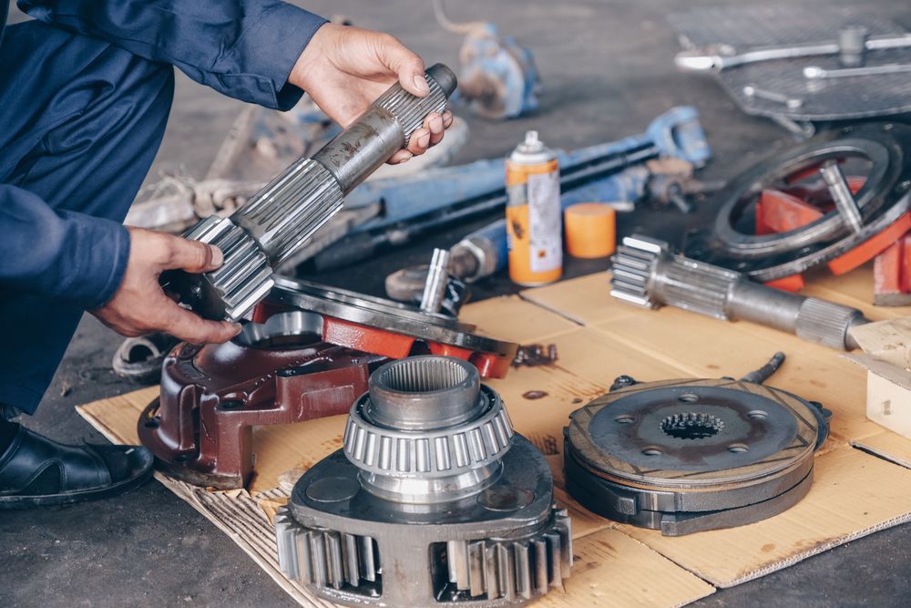 Mechanic Holding Metal Gear, Surrounded by Car Parts on a Cardboard — Prime Mobile Mechanics in Varsity Lakes, QLD