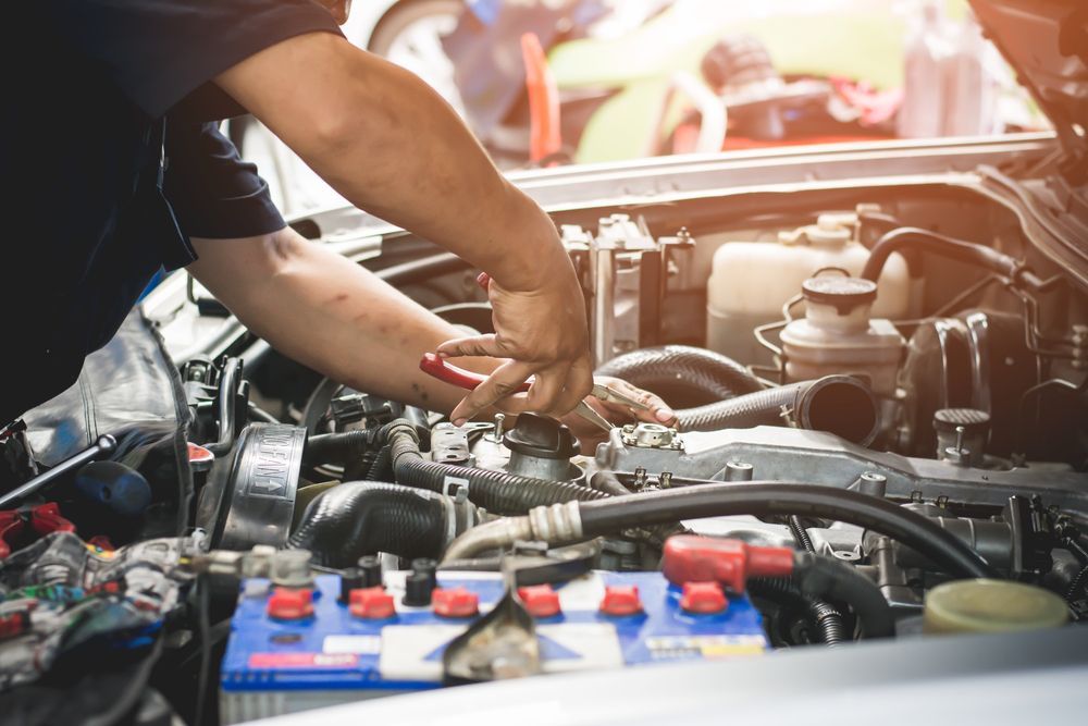 Mechanic working on car engine, using tools under the hood. Bright sunlight — Prime Mobile Mechanics in Varsity Lakes, QLD