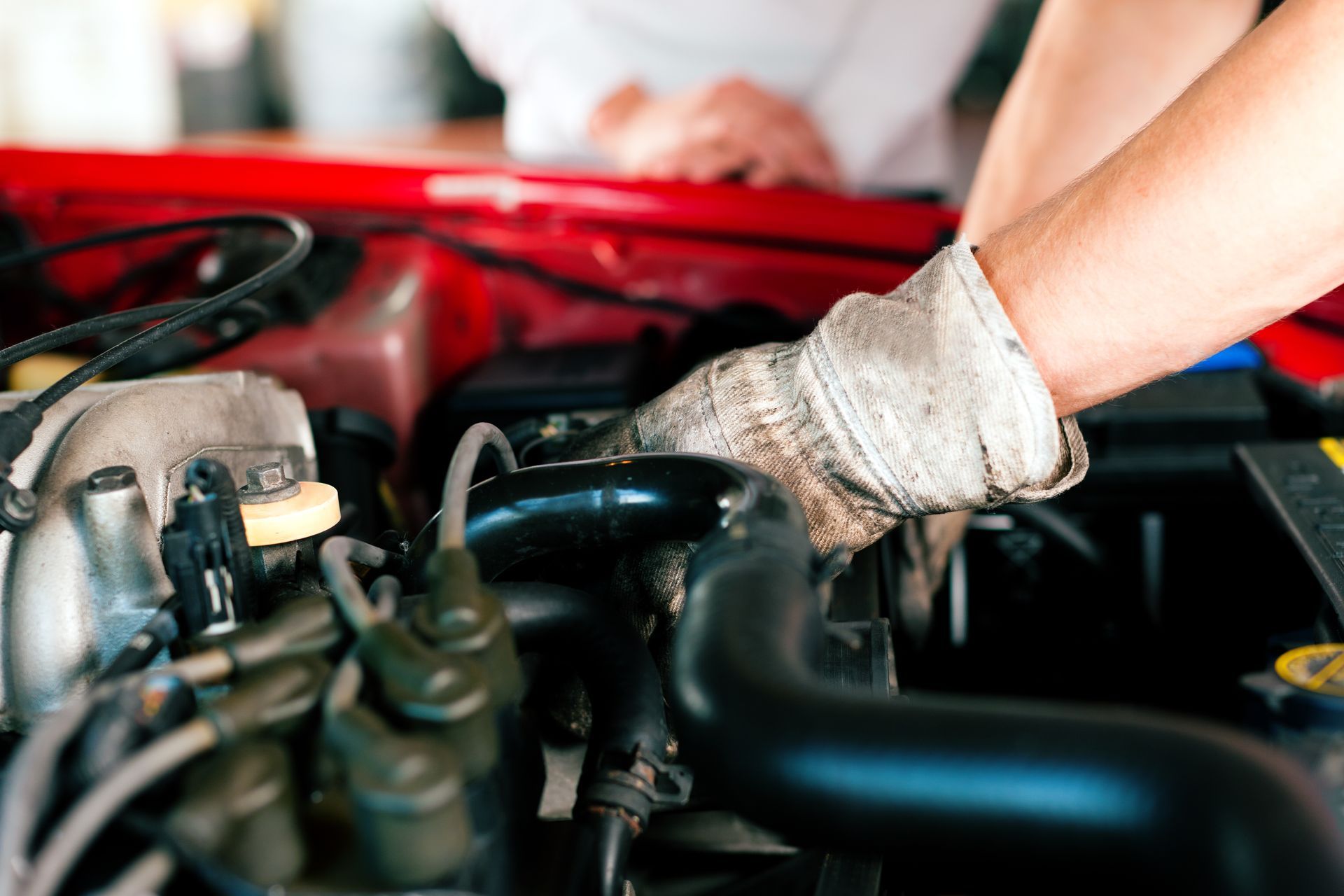 Mechanic with gloved hands working on a red car engine — Prime Mobile Mechanics in Varsity Lakes, QLD