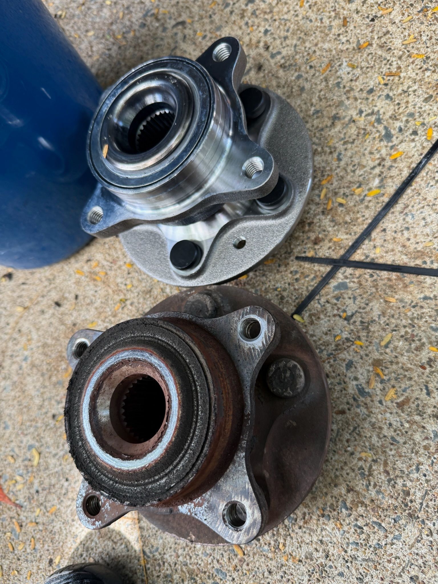 Two car wheel hubs, one new and shiny, one old and rusty, on a surface — Prime Mobile Mechanics in Varsity Lakes, QLD