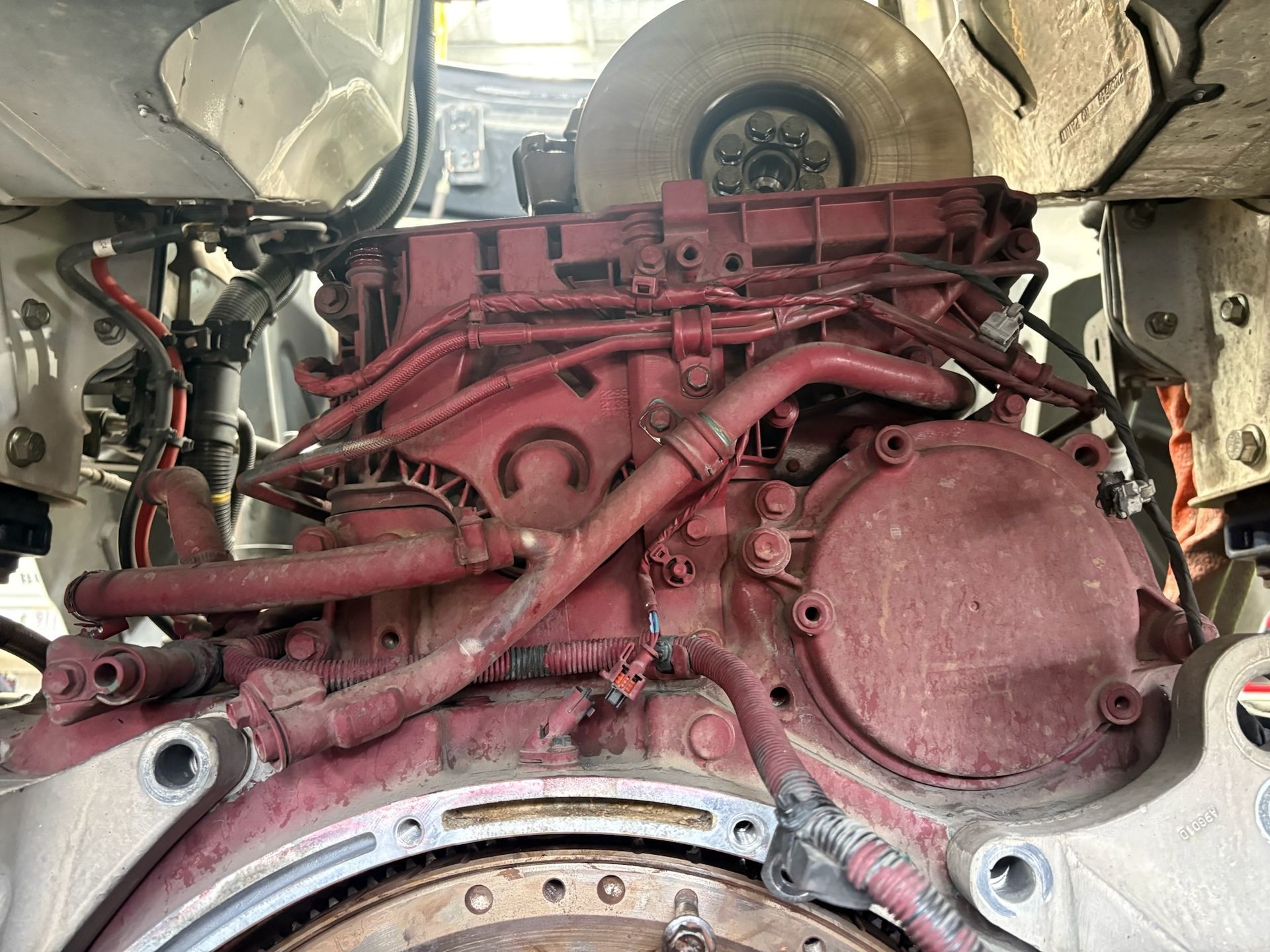 Red-Painted Engine of a Large Vehicle; Visible Wires, Pipes, and a Large Wheel — Prime Mobile Mechanics in Varsity Lakes, QLD