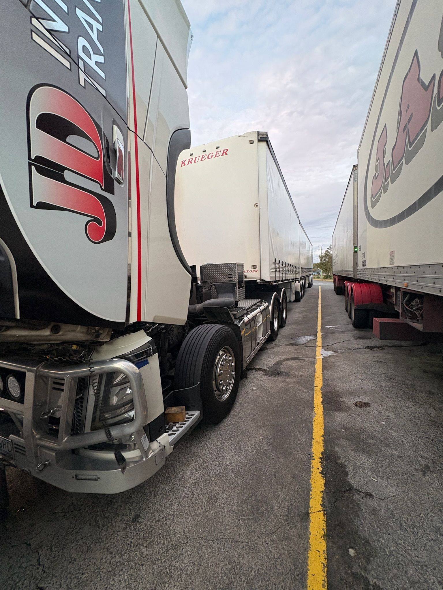 Trucks Parked in a Row on a Gray Asphalt Lot Under a Cloudy Sky — Prime Mobile Mechanics in Varsity Lakes, QLD