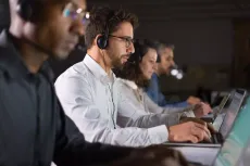 Um grupo de pessoas está trabalhando em laptops em um call center.